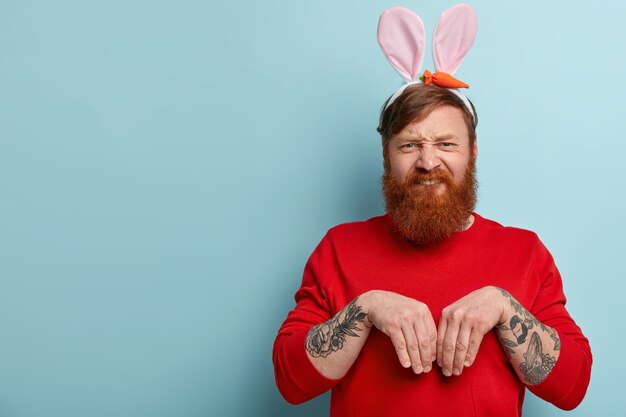 Человек с рыжей бородой в яркой одежде и кроличьих ушах