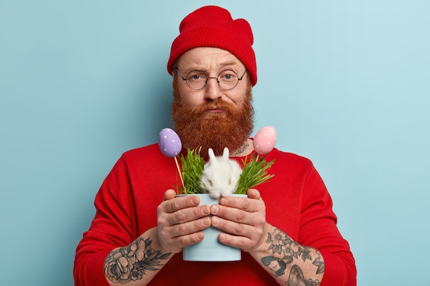 Man with ginger beard wearing colorful clothes holding bunny
