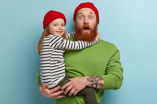 Man with ginger beard wearing colorful clothes holding his daughter