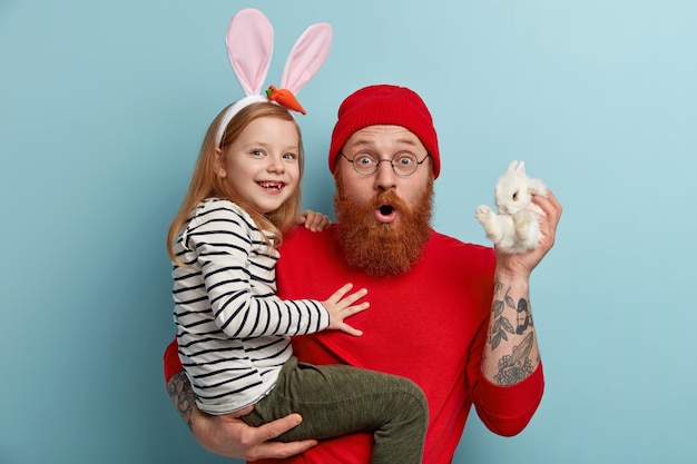 Foto gratuita uomo con la barba allo zenzero che indossa abiti colorati e tiene sua figlia