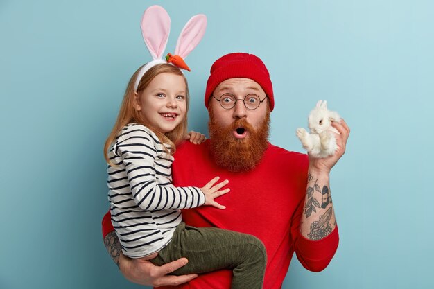 Человек с рыжей бородой в яркой одежде и держит свою дочь