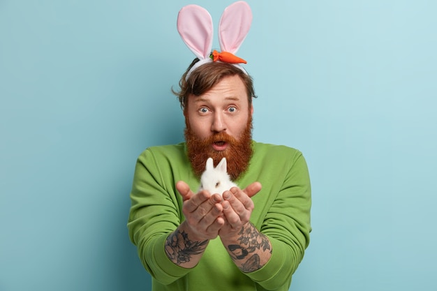 Man with ginger beard wearing colorful clothes holding rabbit