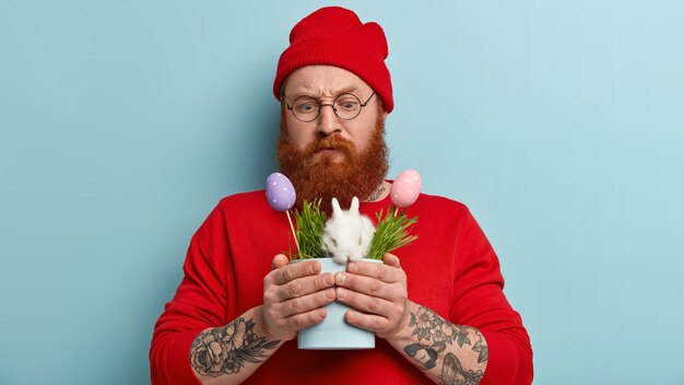 Man with ginger beard wearing colorful clothes and holding rabbit