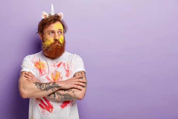 Man with ginger beard wearing unicorn headband and dirty T-shirt