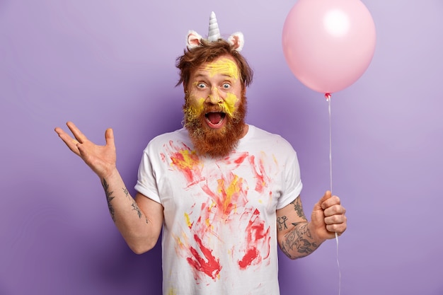Man with ginger beard wearing unicorn headband and dirty T-shirt