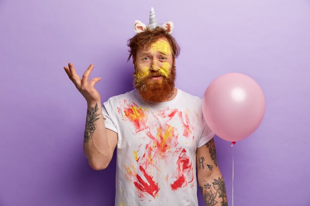 Man with ginger beard wearing unicorn headband and dirty T-shirt