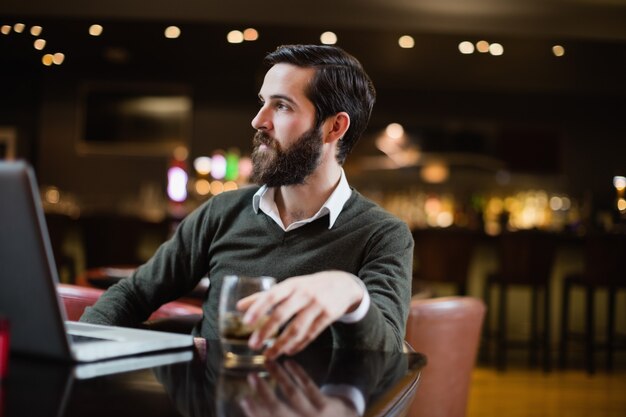 Man with glass of drink and laptop on table