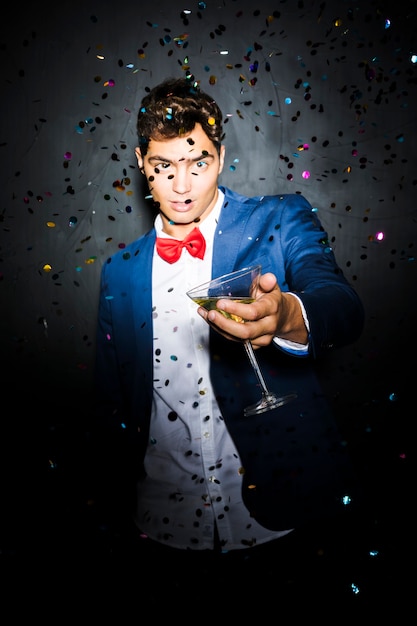 Free photo man with glass between throwing confetti