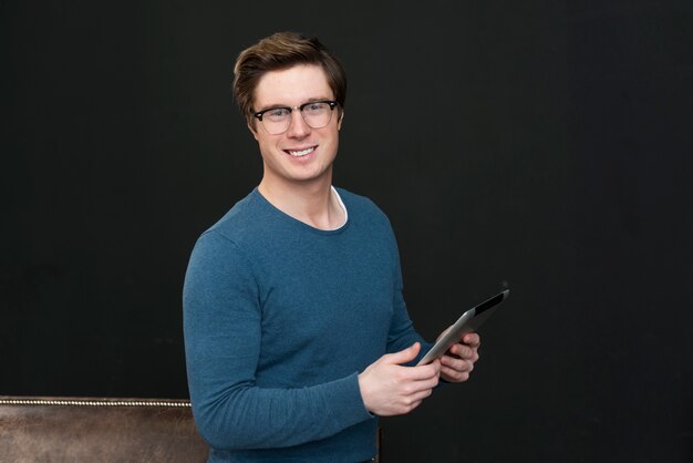 Man with glasses holding a tablet