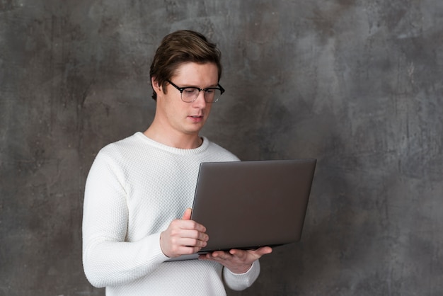 Man with glasses holding up his laptop