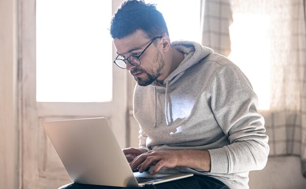 A man with glasses is working on a laptop