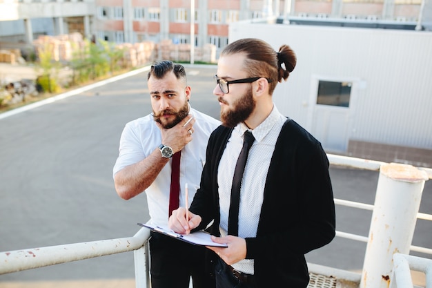 Man with glasses looking at a tablet with another man in the background