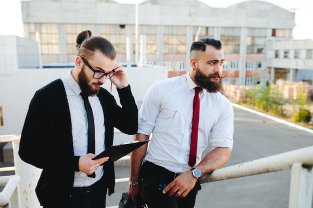 Man with glasses looking at a tablet with another man in the background