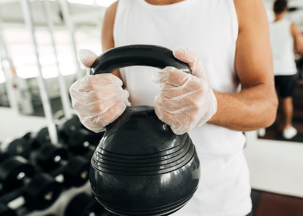 Man with gloves at the gym holding equipment