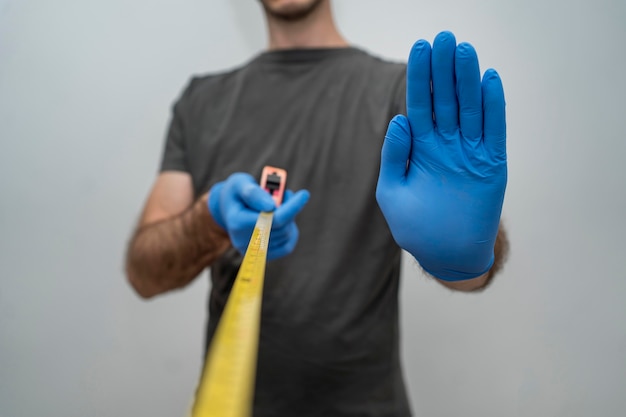 Man with gloves holding tape measurer for social distancing