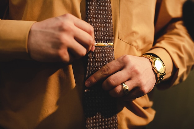 Man with a gold watch adjusts a tie 