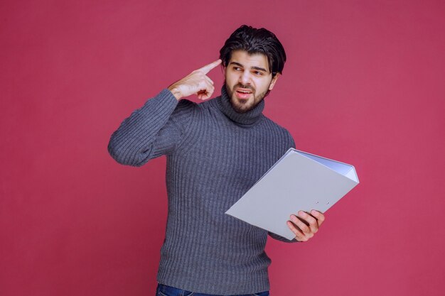 Man with grey folder discussing with the colleagues while checking.