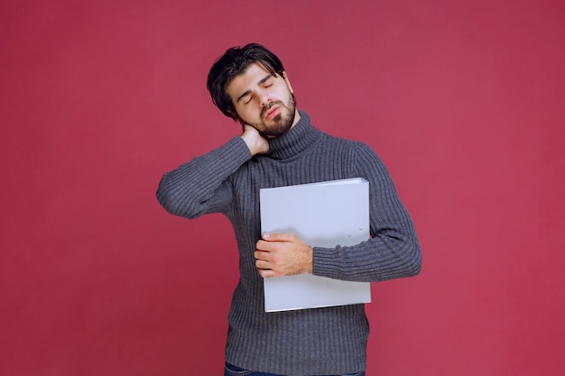 Man with grey folder looks tired and sleepy. 