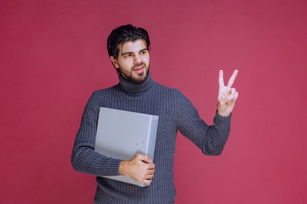 Man with grey folder makes enjoyment hand sign. 