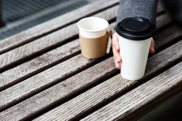 灰色の袖を持つ男は紙のコーヒーを飲む