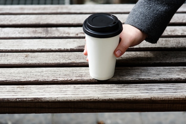 灰色の袖を持つ男は紙のコーヒーを飲む