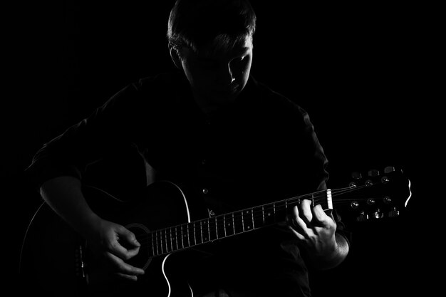 暗闇の中でギターを持つ男