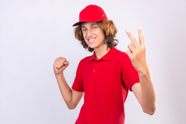 Man with happy face raising fist showing victory sign with fingers over isolated white wall