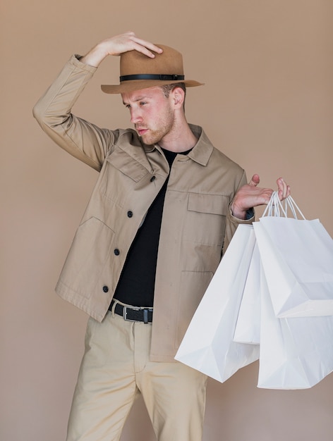 Free photo man with hat on head and shopping bags