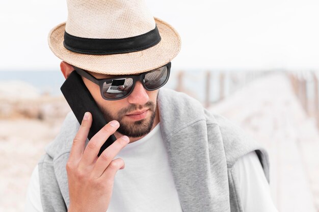 Man with hat and sunglasses talking on smartphones