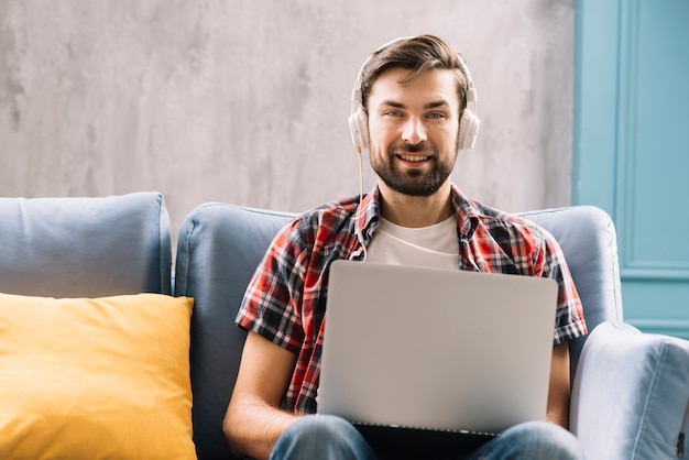 Man with headphones and laptop looking at camera