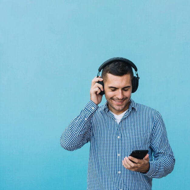 スマートフォンを見ているヘッドホンを持つ男