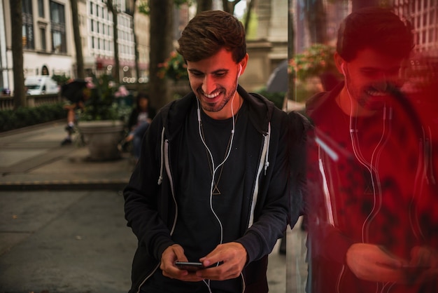 Man with headphones smiling while looking at smartphone