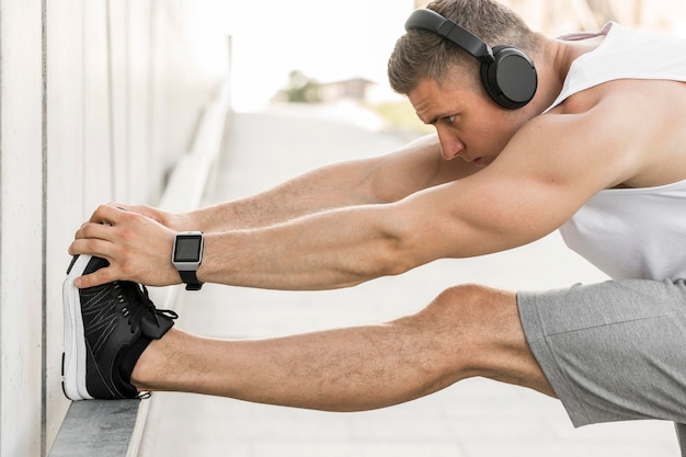 Man with headphones stretching outside