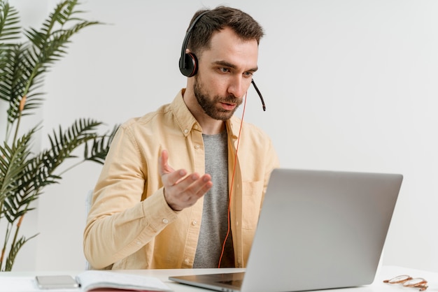 Man with headset having video call on laptop