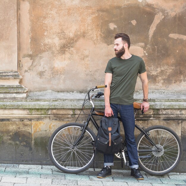 Man with his bicycle standing in front of old wall