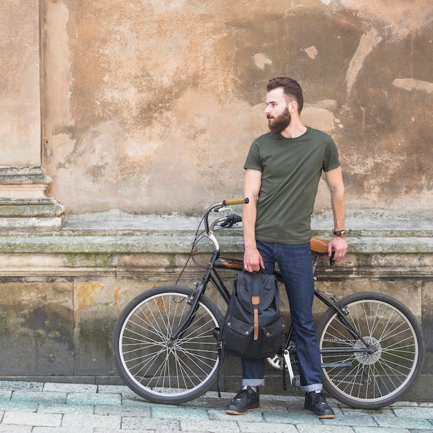 Man with his bicycle standing in front of old wall