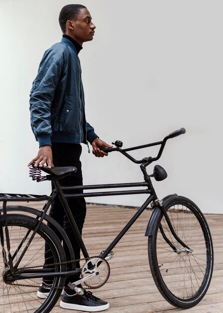 Man with his bicycle next to a wall