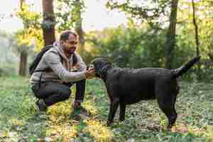 Foto gratuita uomo con il suo labrador nero che gioca nel giardino su erba verde