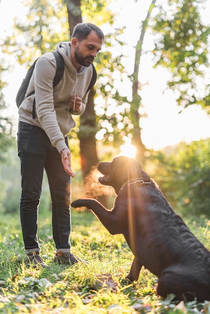 Man with his black labrador playing in park