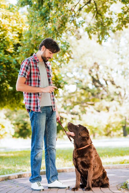 彼の犬を歩いて庭に立っている男