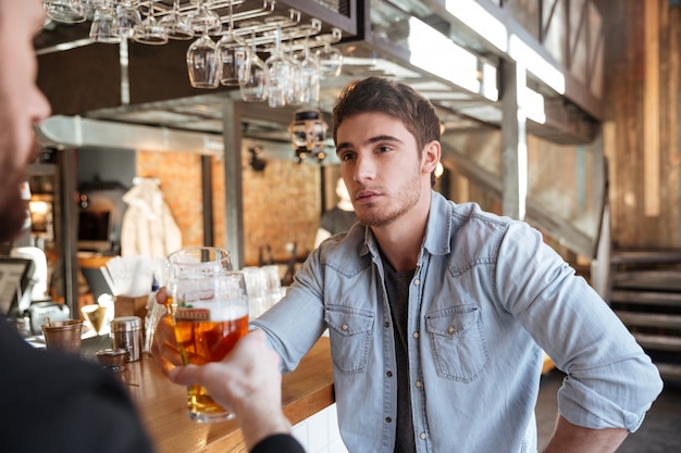 バーでビールを飲む彼の友人を持つ男