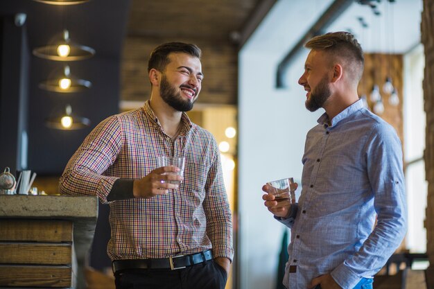 Man with his friend holding glass of whiskey at bar