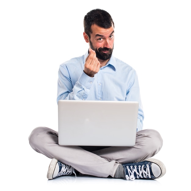 Man with laptop doing money gesture