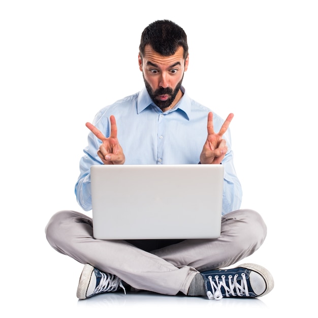 Free photo man with laptop doing victory gesture