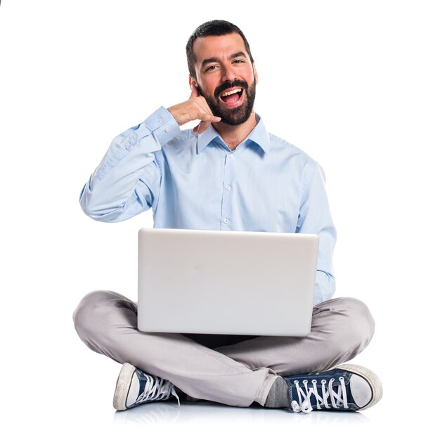 Man with laptop making phone gesture