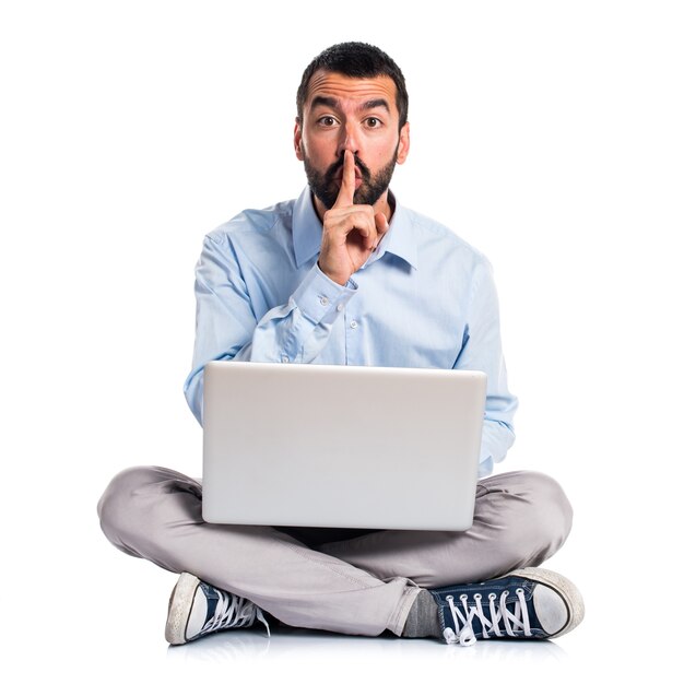 Man with laptop making silence gesture