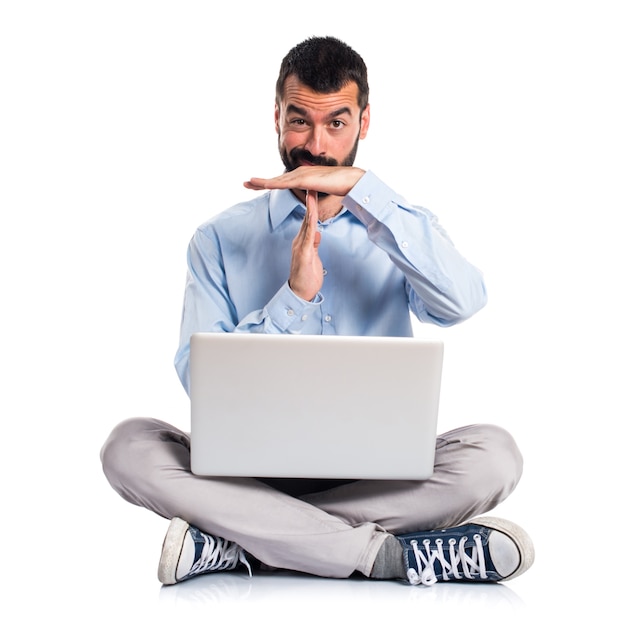 Man with laptop making time out gesture