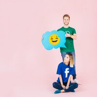 Free photo man with laughing emoji speech bubble standing behind thoughtful woman