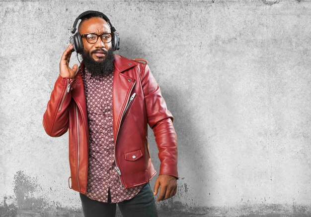 Man with leather jacket listening to music with headphones