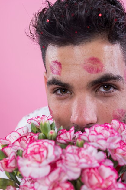 Man with lipstick kiss marks on face with flowers
